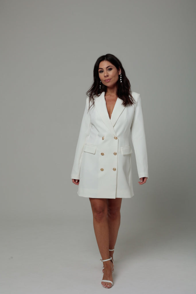 femme portant une robe blazer blanche avec détail boutons dorées